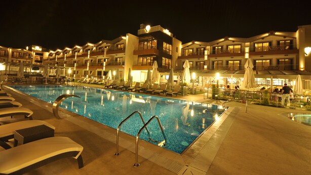 Ein Swimmingpool mit Liegestühlen und Sonnenschirmen, umgeben von Hotelgebäuden mit Balkonen und Außenbereichs-Sitzgelegenheiten.