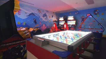 Une pièce équipée d’un baby-foot, de jeux d’arcade et dont un des murs est décoré de motifs représentant la vie marine.