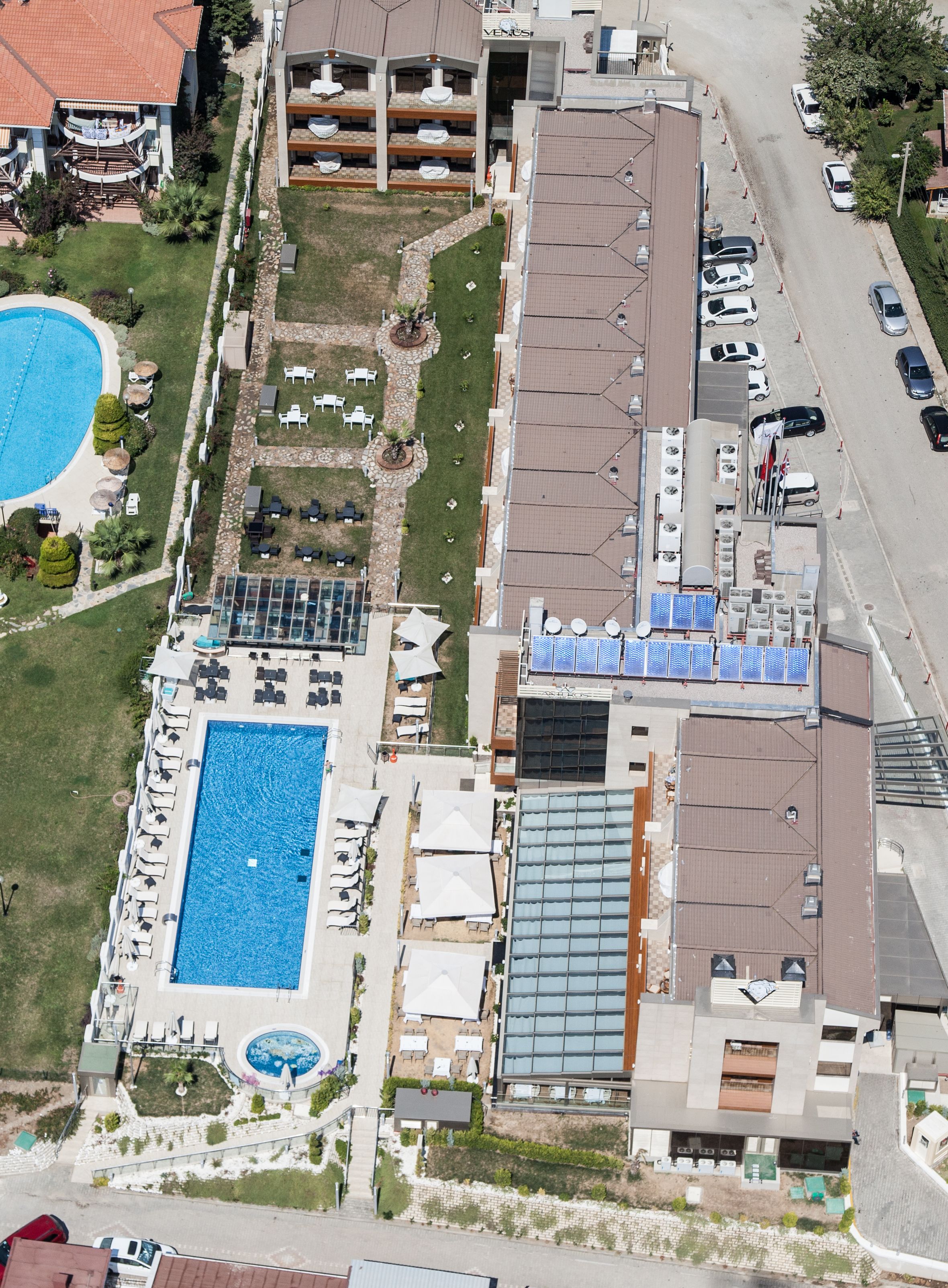 An aerial view of a hotel with a swimming pool, outdoor seating, and a parking area.