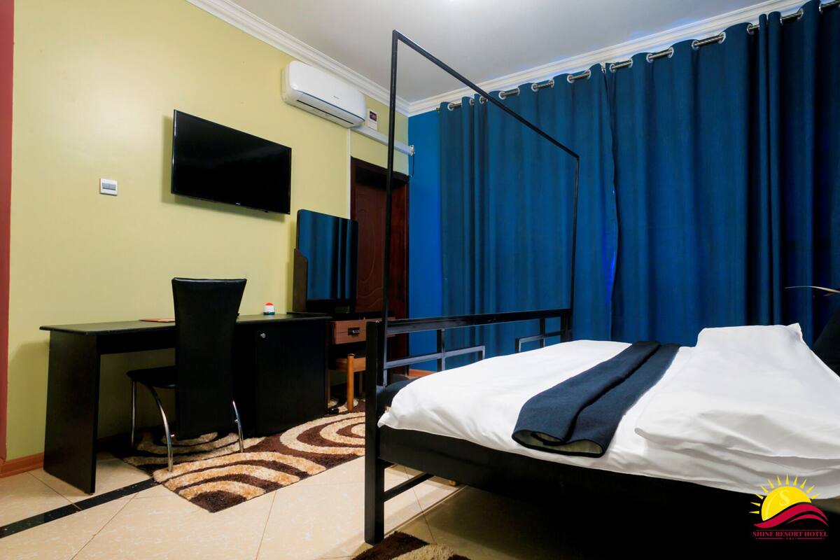 A hotel room with a bed, desk, chair, and a television.