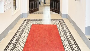 Un couloir avec un tapis rouge, un escalier et une rangée de boîtes aux lettres sur le côté gauche.