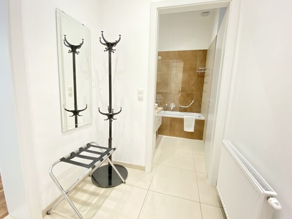 A bathroom with a shower, a towel rack, a mirror, and a radiator.