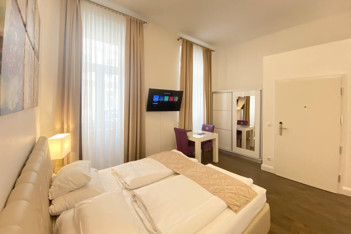 Ein Hotelzimmer mit Bett, Schreibtisch, Stuhl, Fernseher und einer Tür.