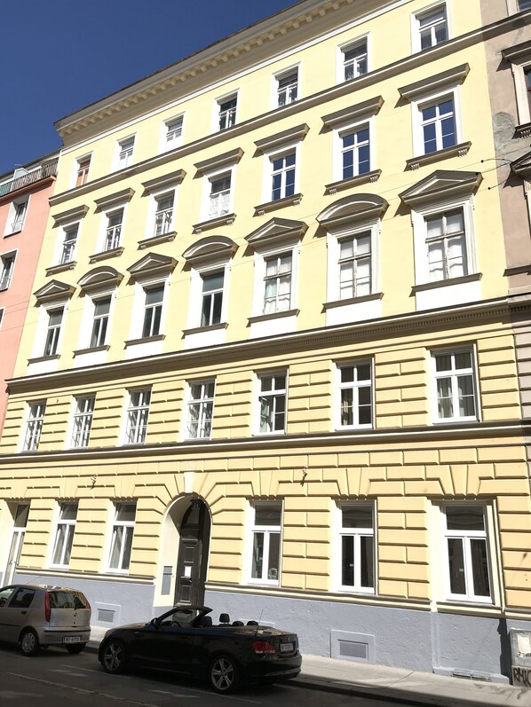 A multi-story building with a yellow facade, multiple windows, and a central entrance with a door. - Steiner Residences Vienna Taborstrasse (Vienna)