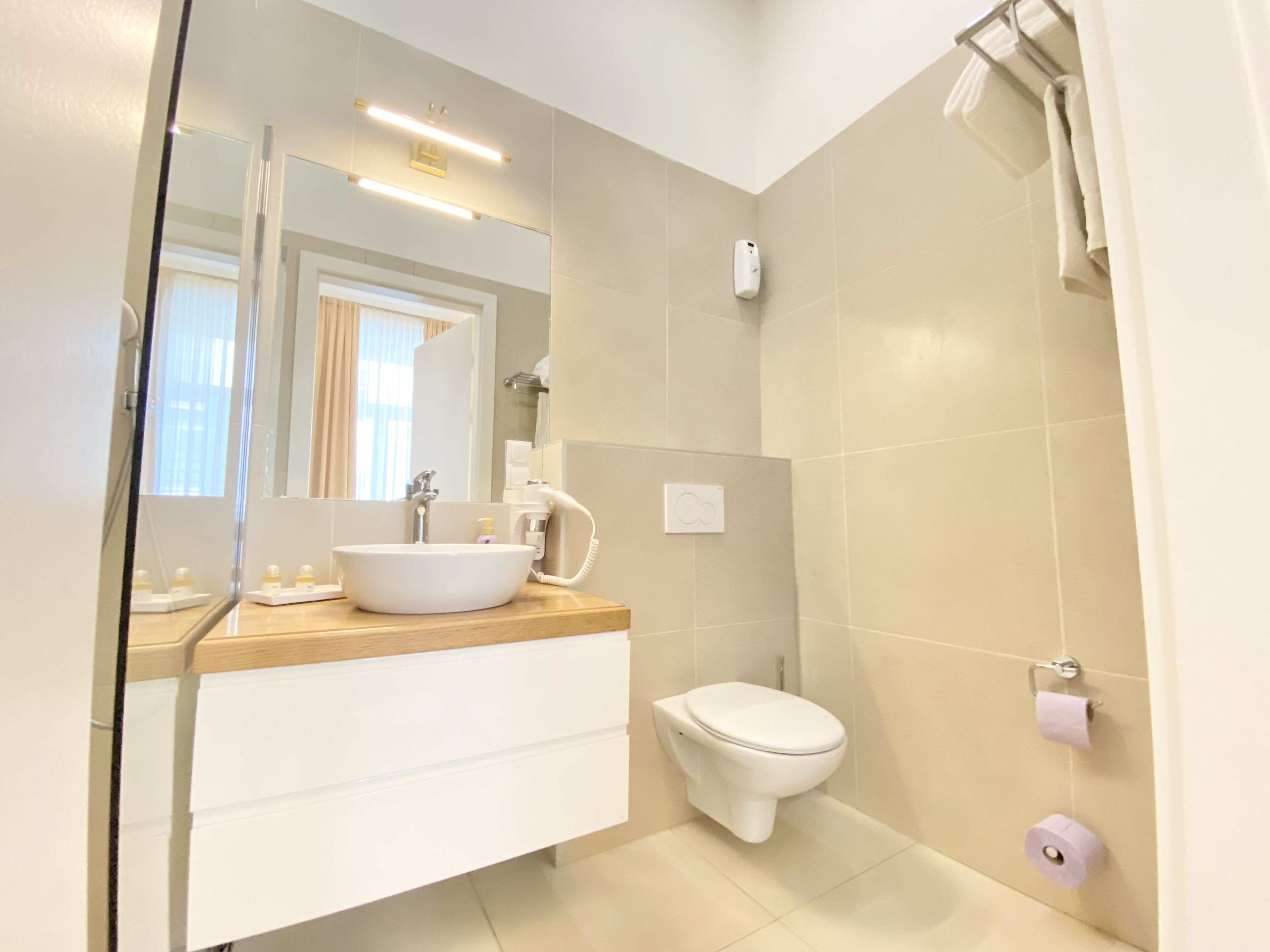 Een moderne badkamer met een wit wastafel, een toilet en een spiegel.