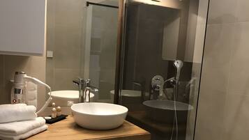 Ein modernes Badezimmer mit einem Holzwaschtisch, einem weißen Waschbecken und einer Duschkabine.