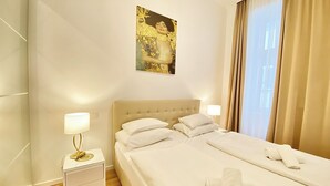 Une chambre d’hôtel avec un grand lit, deux tables de chevet, un tableau accroché au mur et une fenêtre avec des rideaux.
