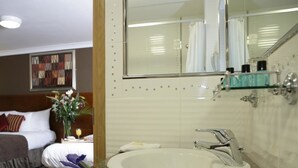 A hotel bathroom with a round sink, a mirror, and a shower area. - Ashford Court Boutique Hotel (Ennis)