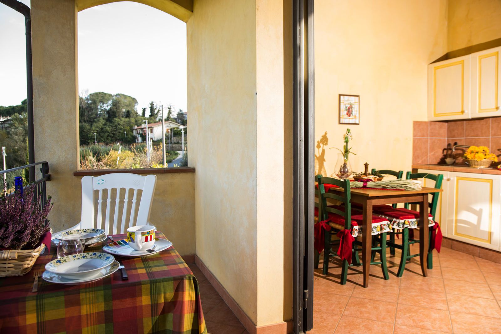 A balcony with a table set for two, a chair, and a view of the outdoors.