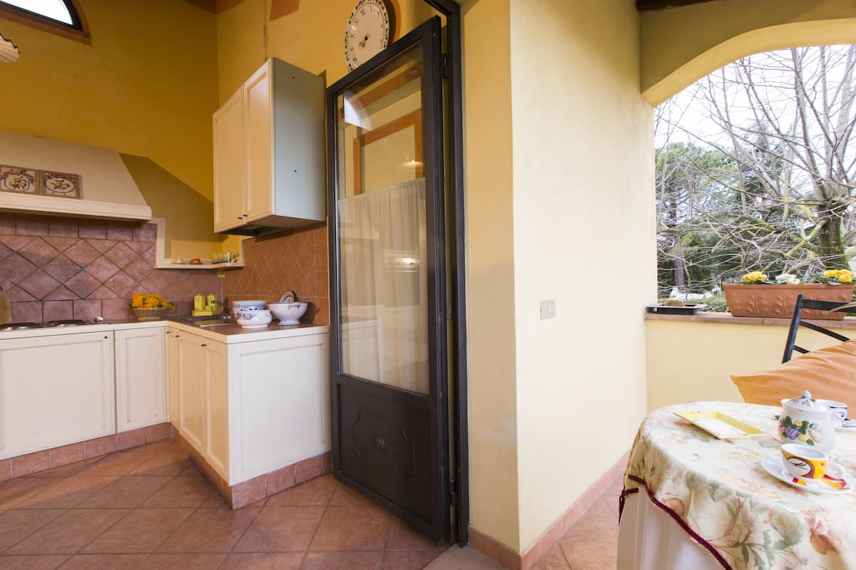 A kitchen with white cabinets, a tiled backsplash, and a window overlooking a garden.