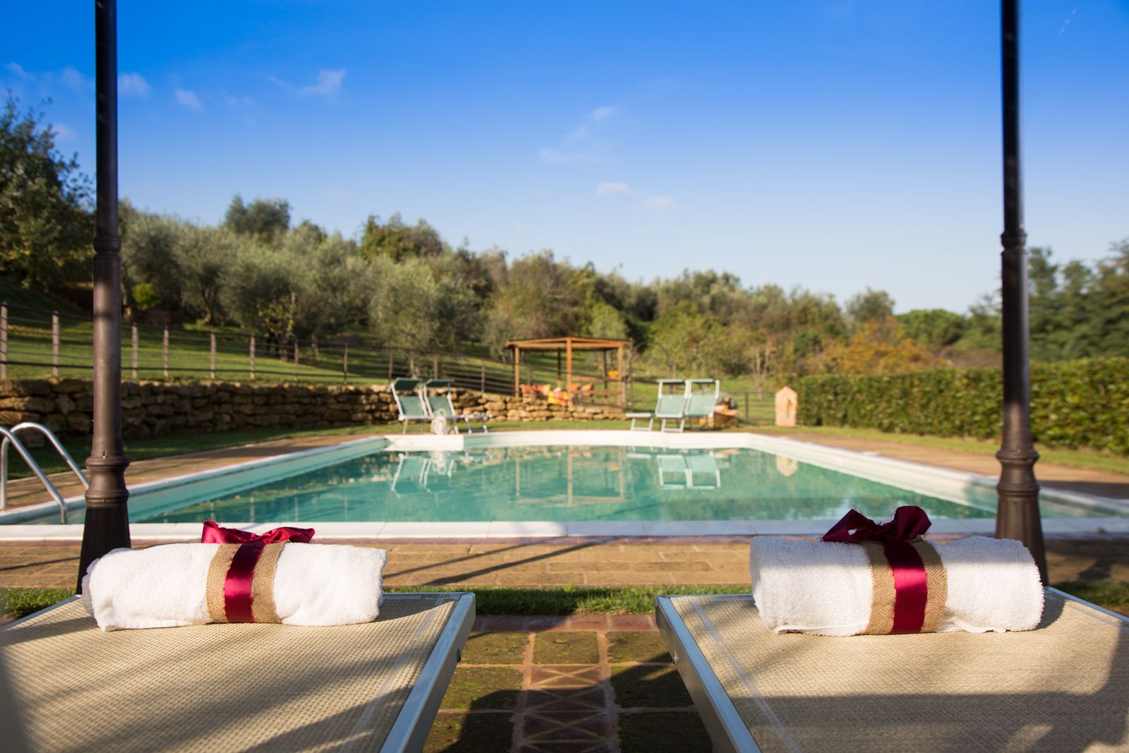 Ein Poolbereich mit Liegestühlen und einer Pergola im Hintergrund.