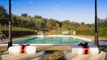 Ein Poolbereich mit Liegestühlen und einer Pergola im Hintergrund.