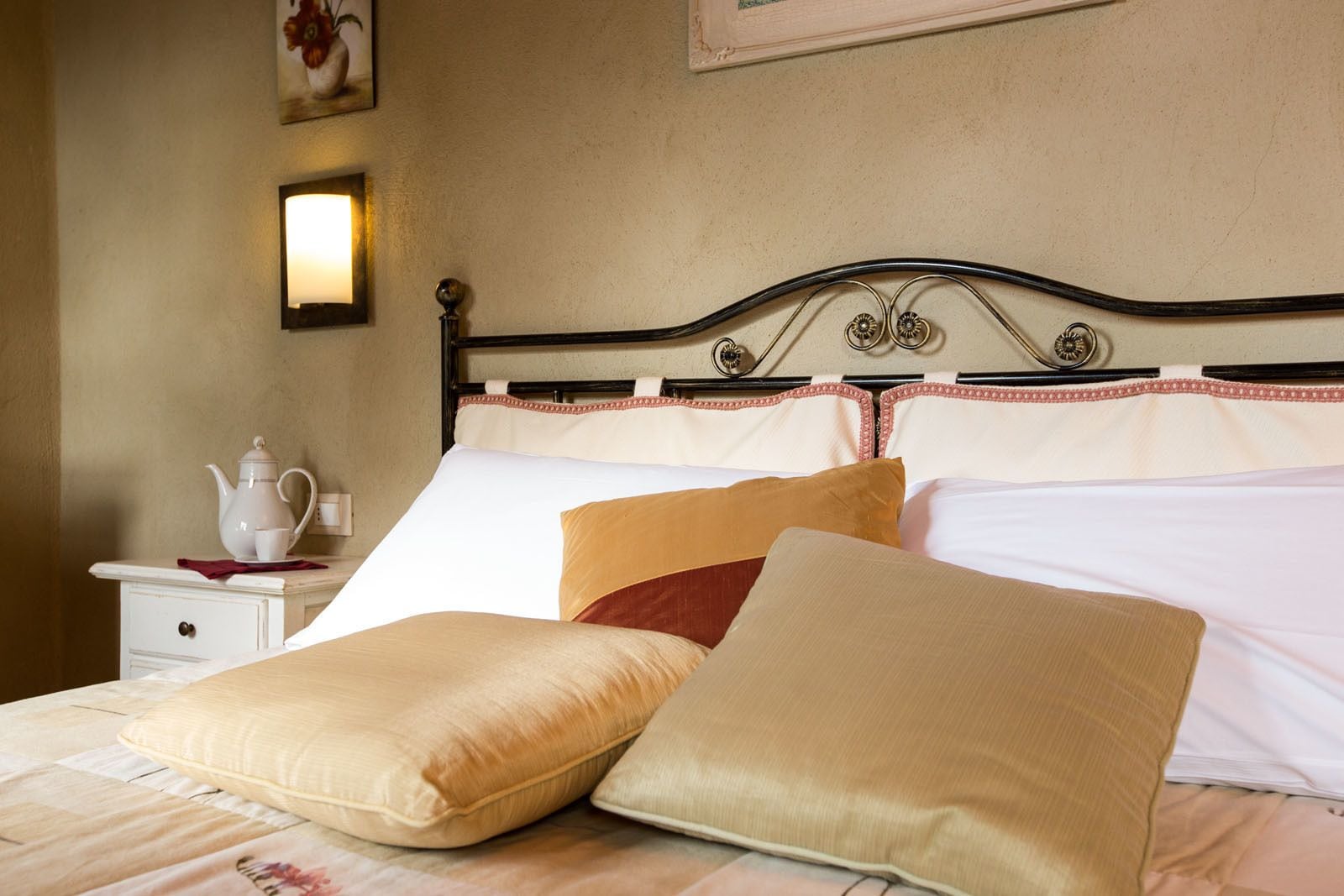 A neatly made bed with a metal headboard, white linens, and multiple pillows.