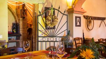 A restaurant interior with a brick wall, a metal gate with a floral decoration, and a table set for dining.