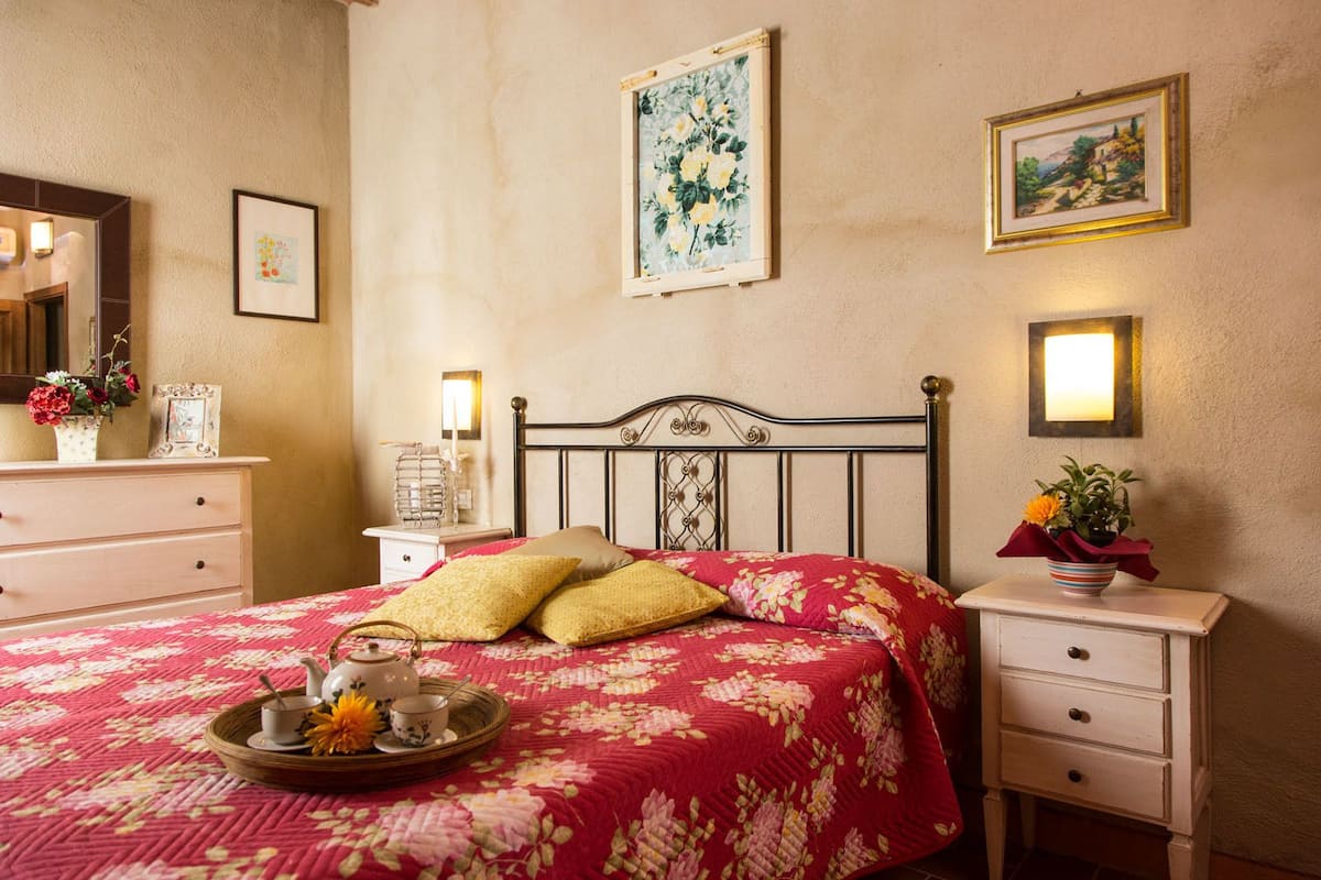 A bedroom with a bed, bedside tables, a dresser, and wall-mounted lights.