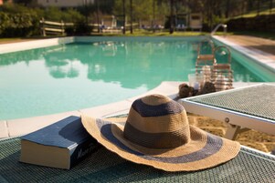 Una piscina al aire libre de temporada, sombrillas