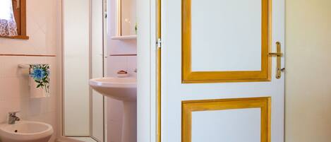 A bathroom with a toilet, bidet, sink, and mirror.
