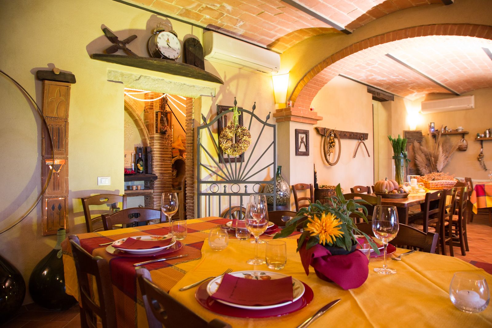 A dining area with a brick fireplace, wooden furniture, and a decorative wreath on the wall.