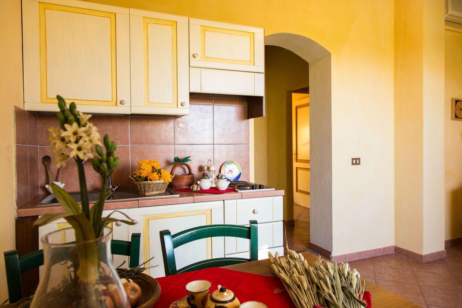 A kitchen with white cabinets, a red tablecloth, and various kitchen items.