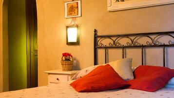 Un dormitorio con cama, mesita de noche, lámpara de pared, cuadro enmarcado y una puerta.
