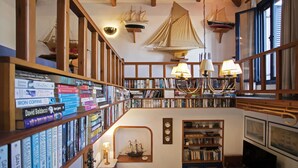 Une bibliothèque avec des étagères, une maquette de bateau et un téléviseur.