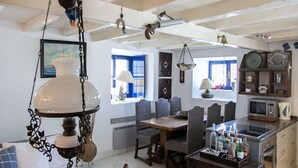 Une cuisine chaleureuse, avec des meubles en bois, un luminaire suspendu et une vue sur la mer par la fenêtre.