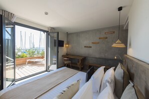 A modern bedroom with a large bed, a desk, and a view through a sliding glass door to an outdoor deck. - L'Anderenis (Andernos-les-Bains)