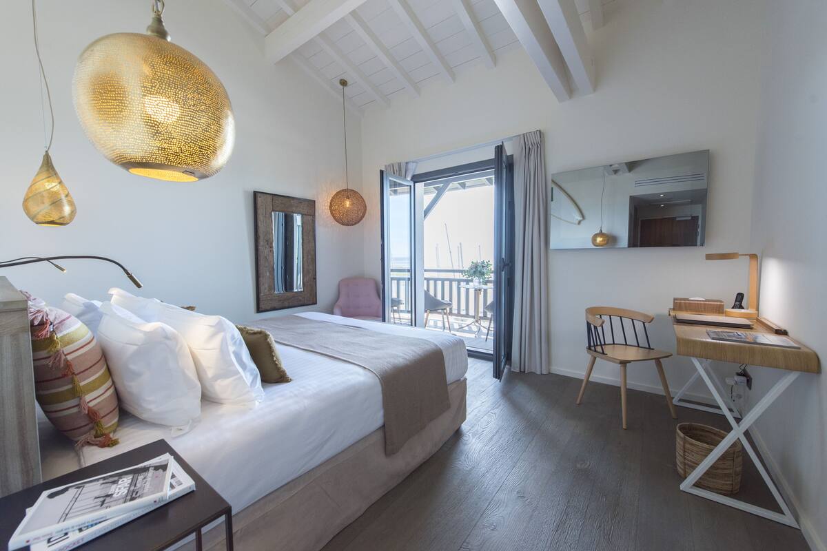 Quarto com cama, escrivaninha e cadeira. Janela com vista para o exterior.