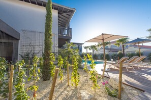 A poolside area with a wooden deck, lounge chairs, and a pergola with climbing plants. - L'Anderenis (Andernos-les-Bains)