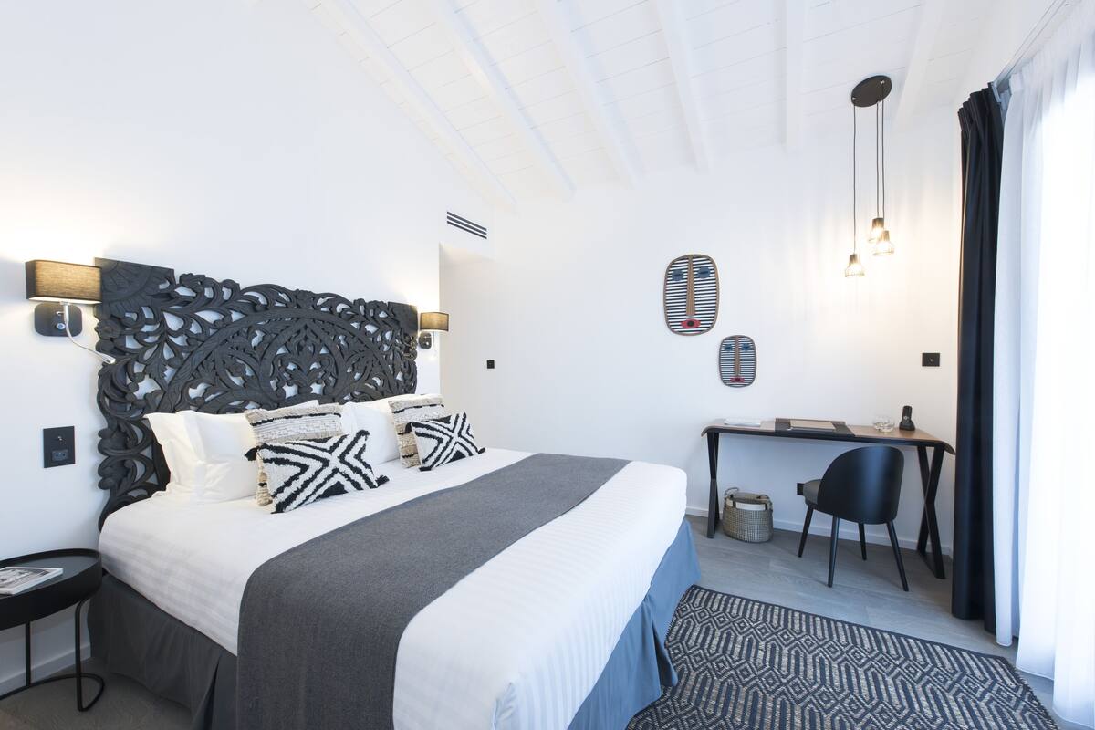 Quarto de hotel moderno com uma cama grande, uma escrivaninha e uma cadeira.