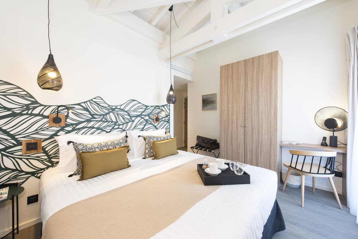Quarto de hotel moderno com uma cama grande, uma escrivaninha e uma cadeira.