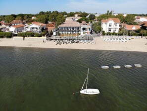 A coastal area with a beach, houses, and a sailboat anchored near the shore. - L'Anderenis (Andernos-les-Bains)