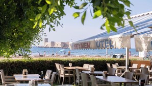 Outdoor seating with tables and chairs, a view of the sea, and a building with 'SEYMEN OTER' signage.