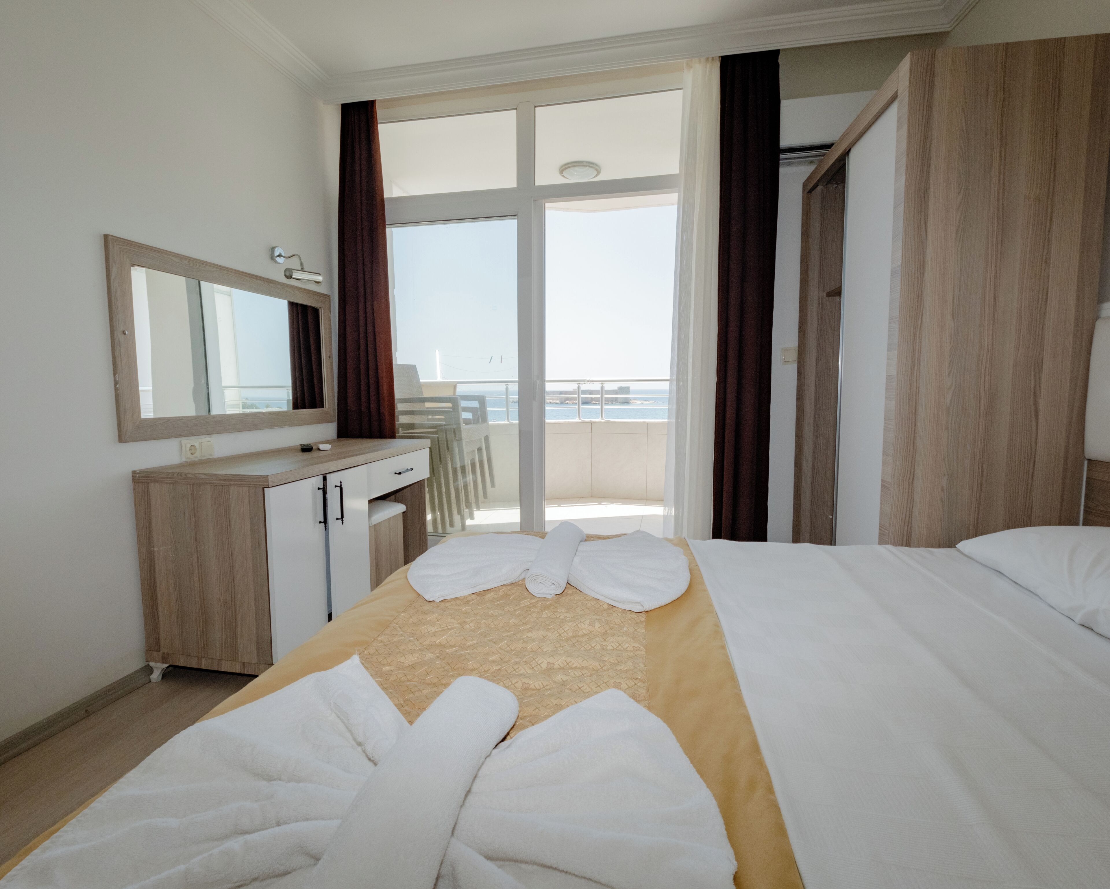 Habitación de hotel con cama, escritorio, espejo y vista al mar.