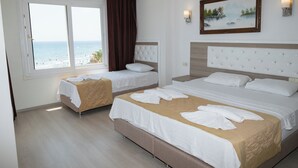 A hotel room with two beds, a large window with a view of the sea, and a painting on the wall.