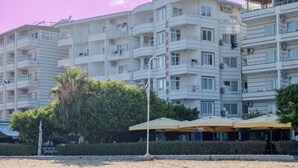 A beachfront hotel with multiple balconies, a sandy beach, and a wooden boardwalk.