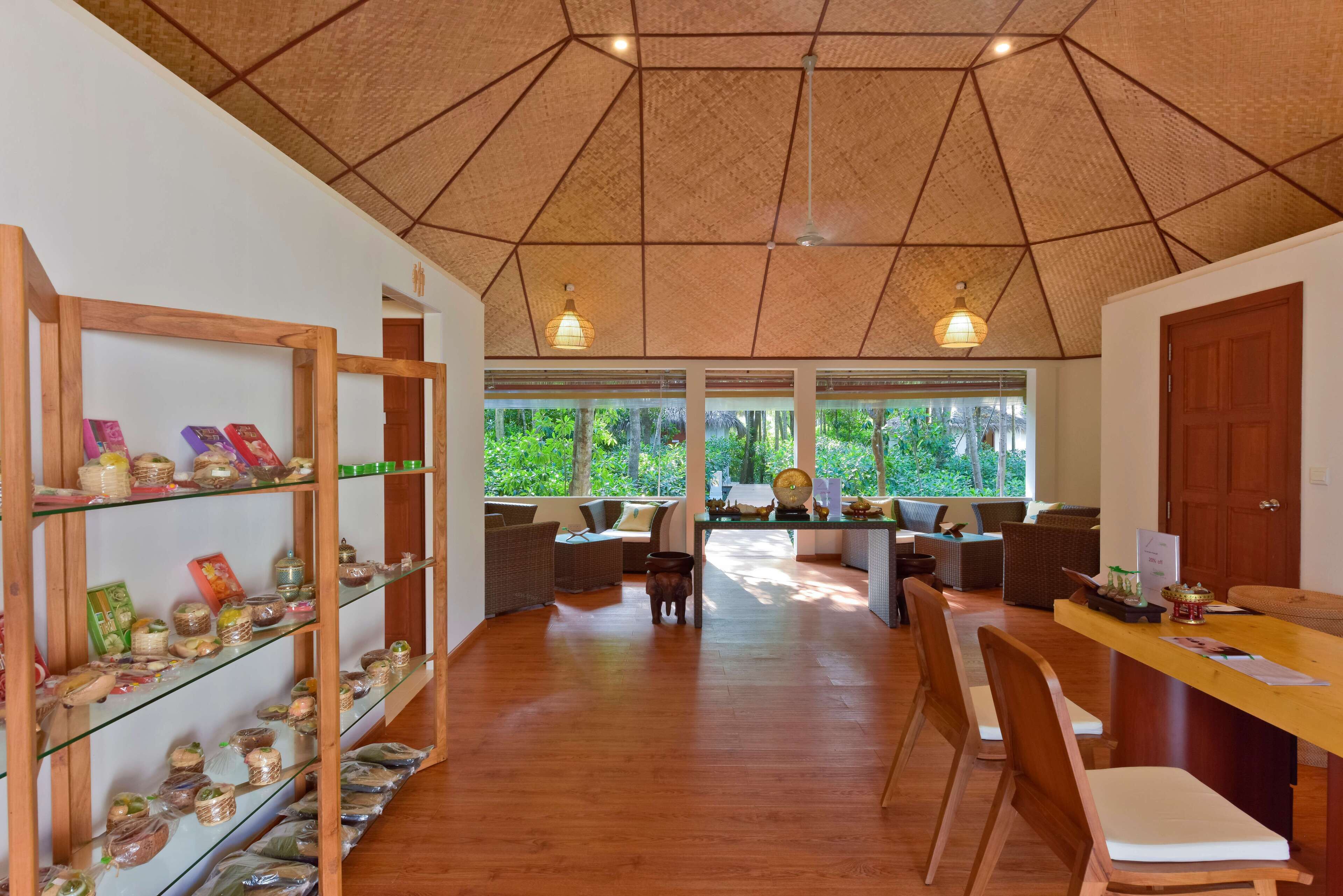 A spacious room with a wooden ceiling, large windows, and a central seating area with sofas and chairs.