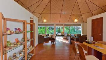 Una habitación amplia con techo de madera, ventanas grandes y una zona de estar central con sofás y sillones.