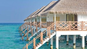 Cabañas sobre el agua con techos de paja y barandillas de madera, conectadas por escaleras.