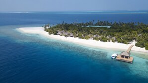 Vista aérea de un resort en una isla tropical con playas de arena blanca, exuberante vegetación y aguas azules cristalinas.