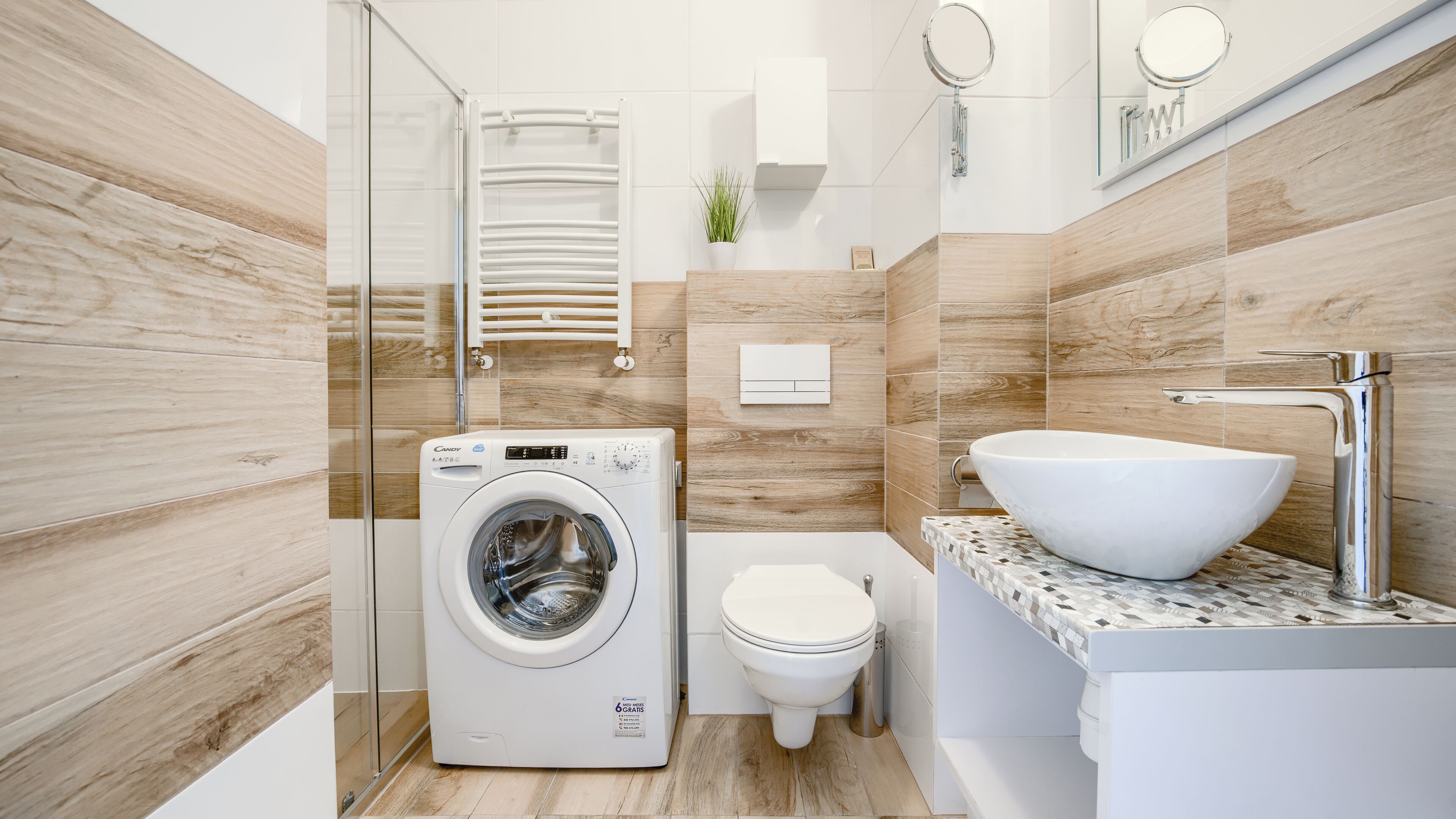 Une salle de bain moderne équipée d’un lave-linge intégré, de toilettes et d’un grand lavabo avec un plan de travail en marbre.