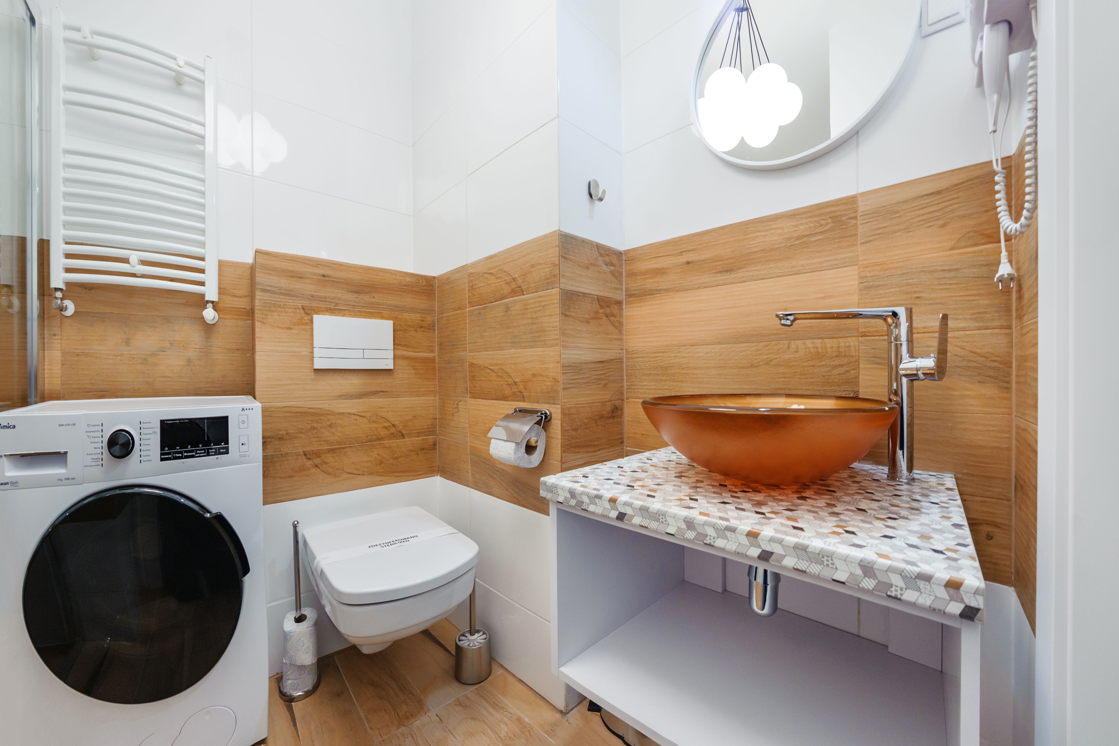 Une salle de bain moderne équipée d’un lave-linge, de toilettes, d’un lavabo et de carreaux de mur en bois.