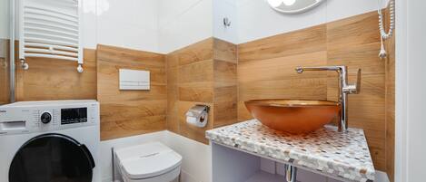 Une salle de bain moderne équipée d’un lave-linge, de toilettes, d’un lavabo et de carreaux de mur en bois.