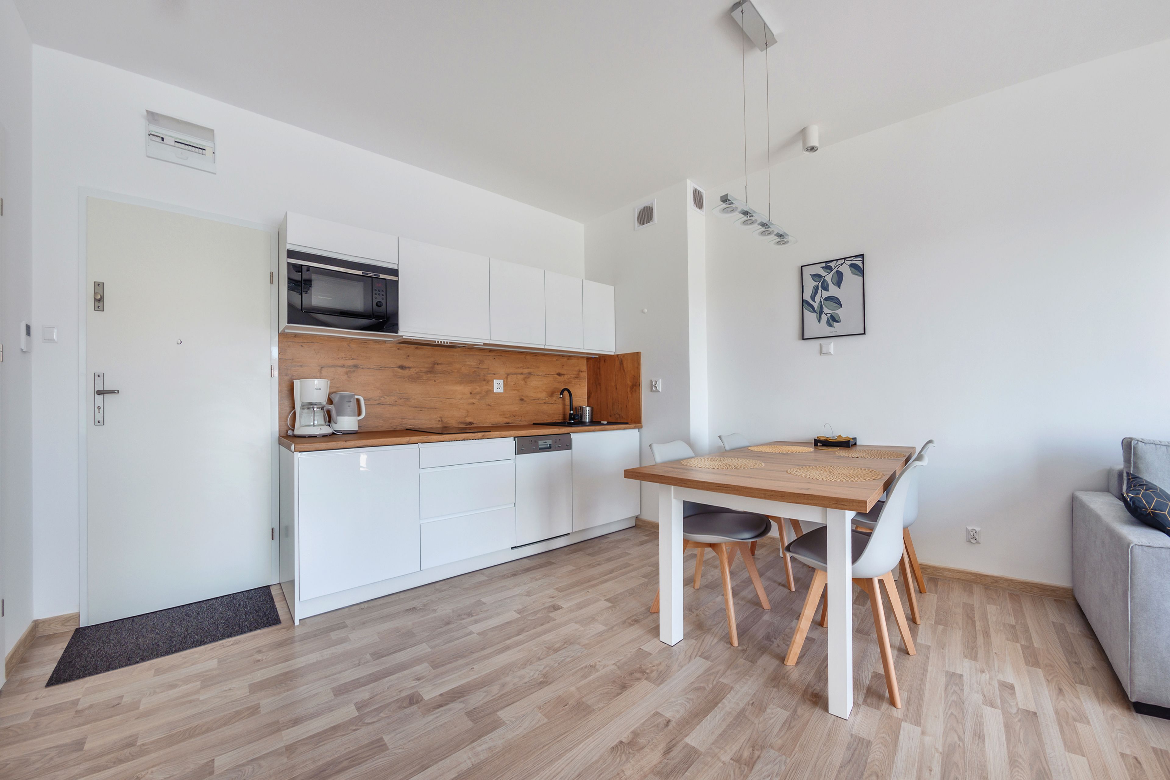 A modern kitchen with white cabinets, a wooden countertop, and a dining area with a wooden table and chairs.