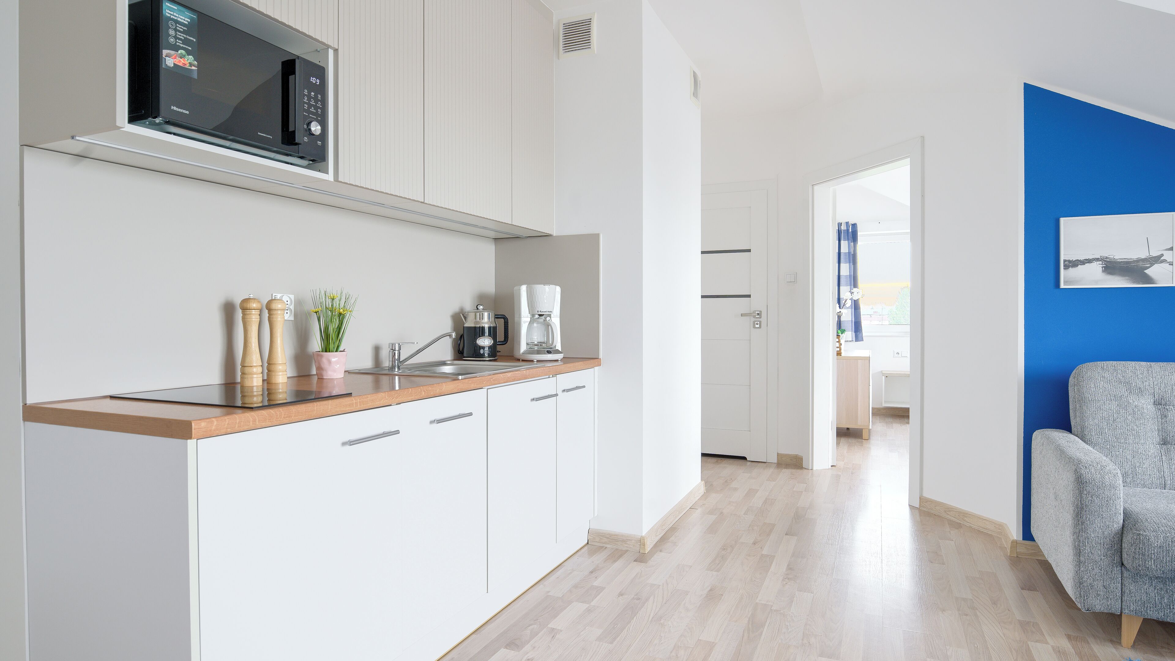 A modern kitchen with a microwave, coffee maker, and a potted plant.