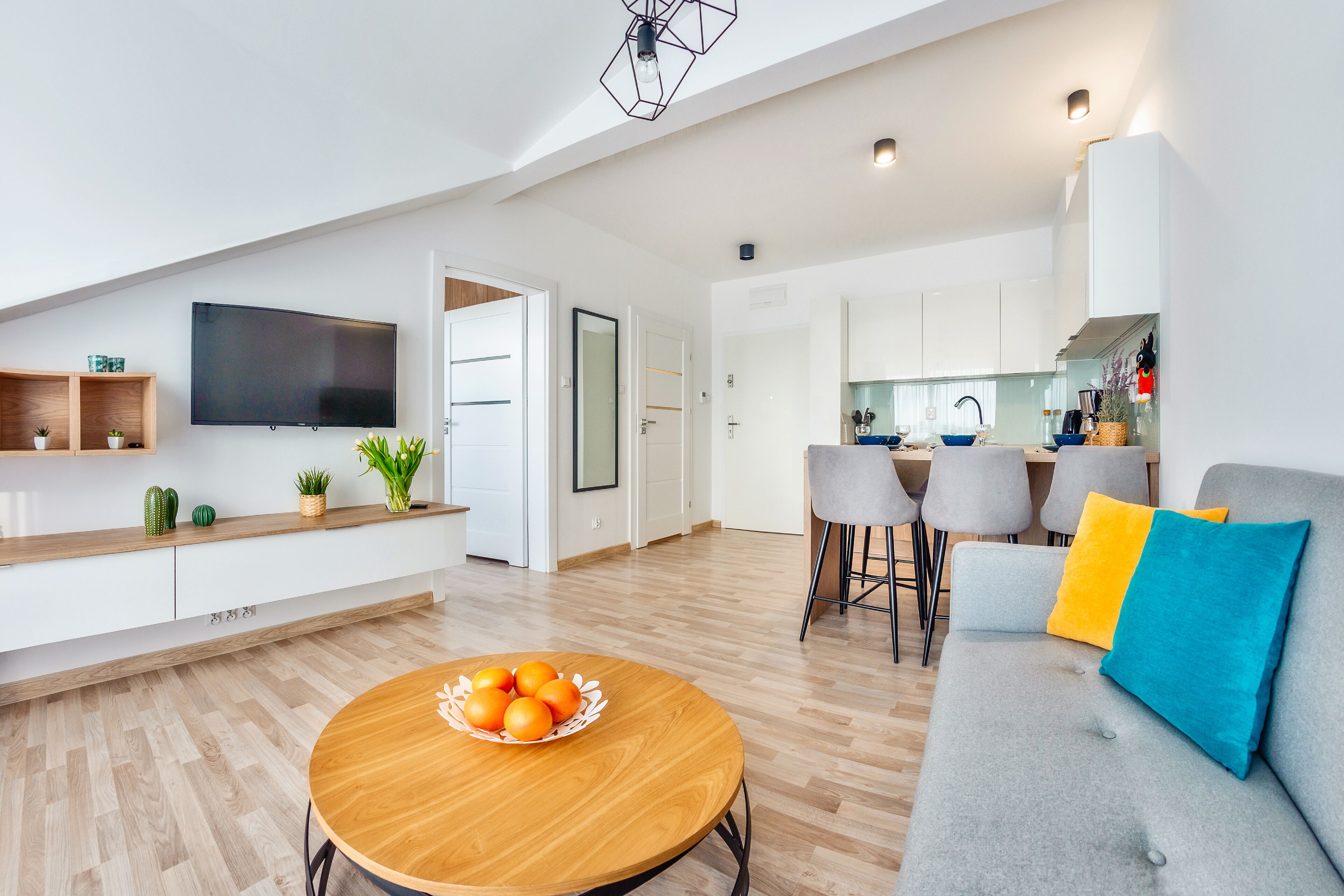 Een moderne woonkamer met een houten salontafel, een grijze bank en een flatscreen televisie.