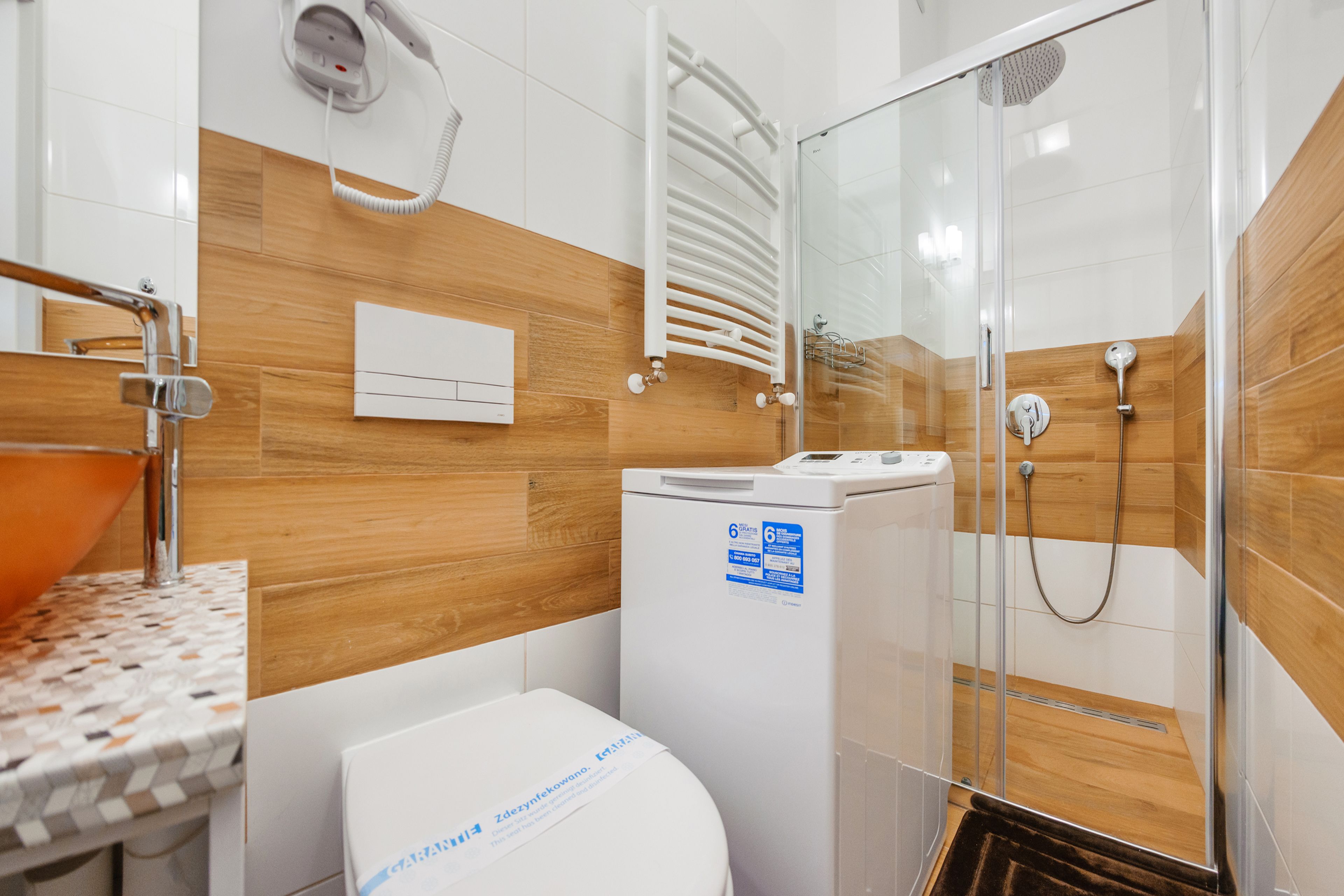 Un baño moderno con ducha, inodoro y lavadora.