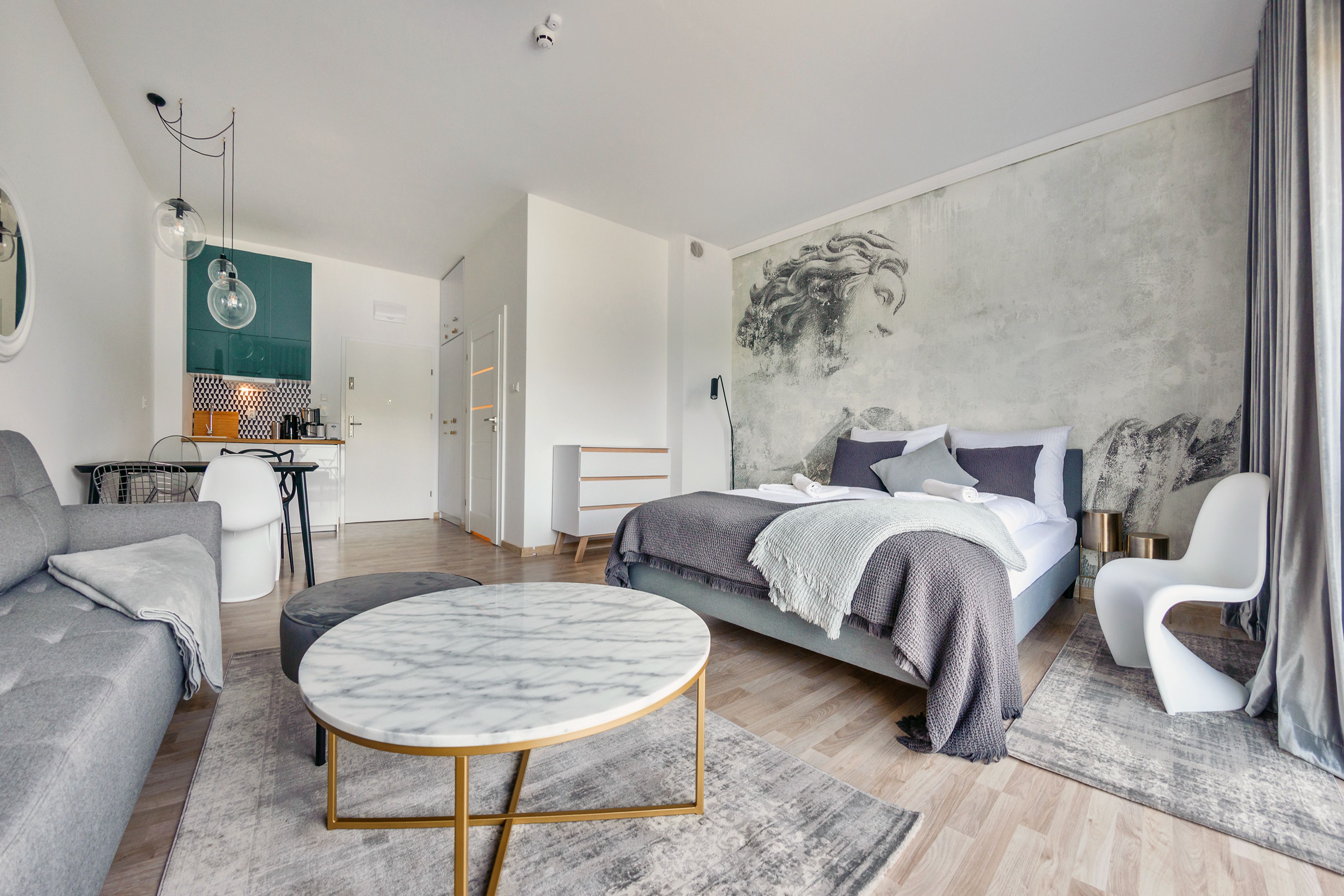 Une chambre moderne comprenant un lit, un canapé, une table ronde et un coin repas avec des chaises.
