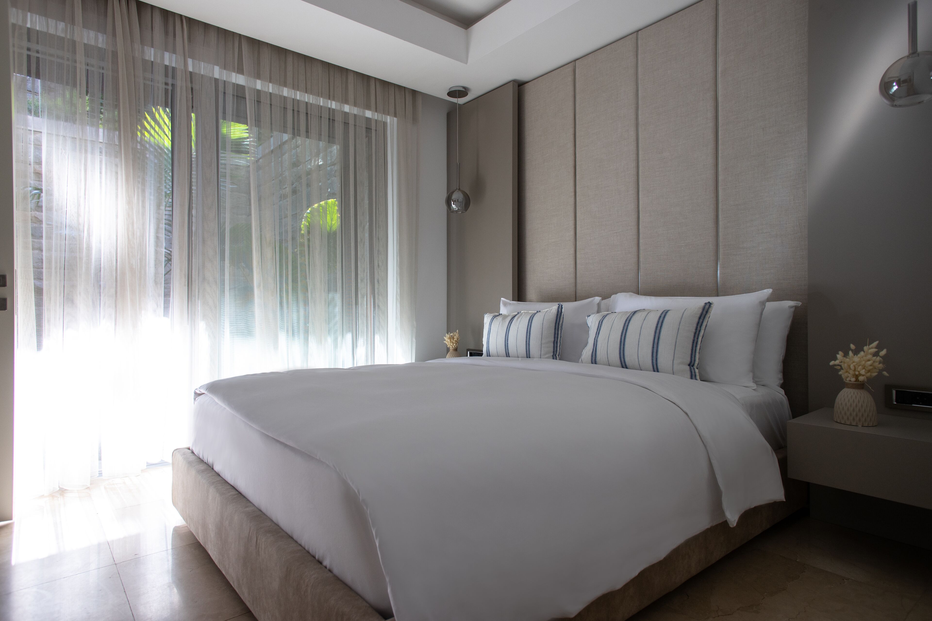 A modern bedroom with a large bed, a nightstand, and a wall-mounted lamp.