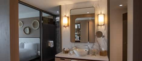 A modern bathroom with a large mirror, a white sink, and a shower area.